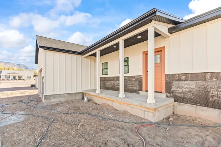 Front porch entry with a salmon-toned door, vertical board siding, and black trim accents