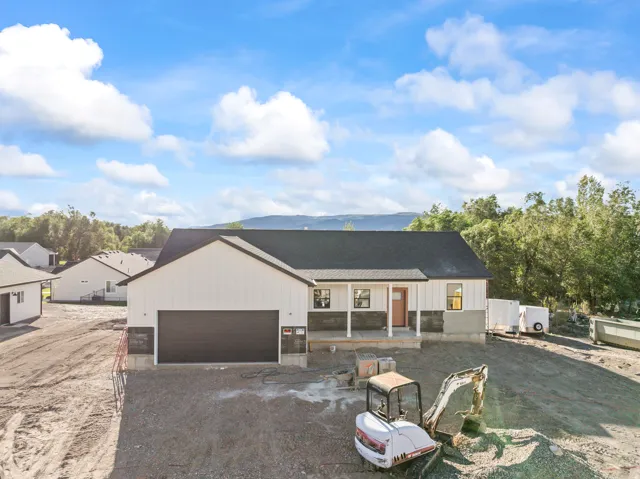 Modern farmhouse exterior with white vertical siding, dark roof, two-car garage, covered porch, and stone accents