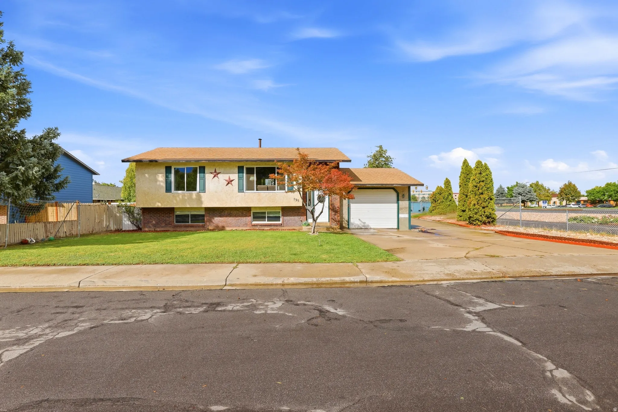 Split-level residence featuring a one-car garage, established front lawn, and mature trees