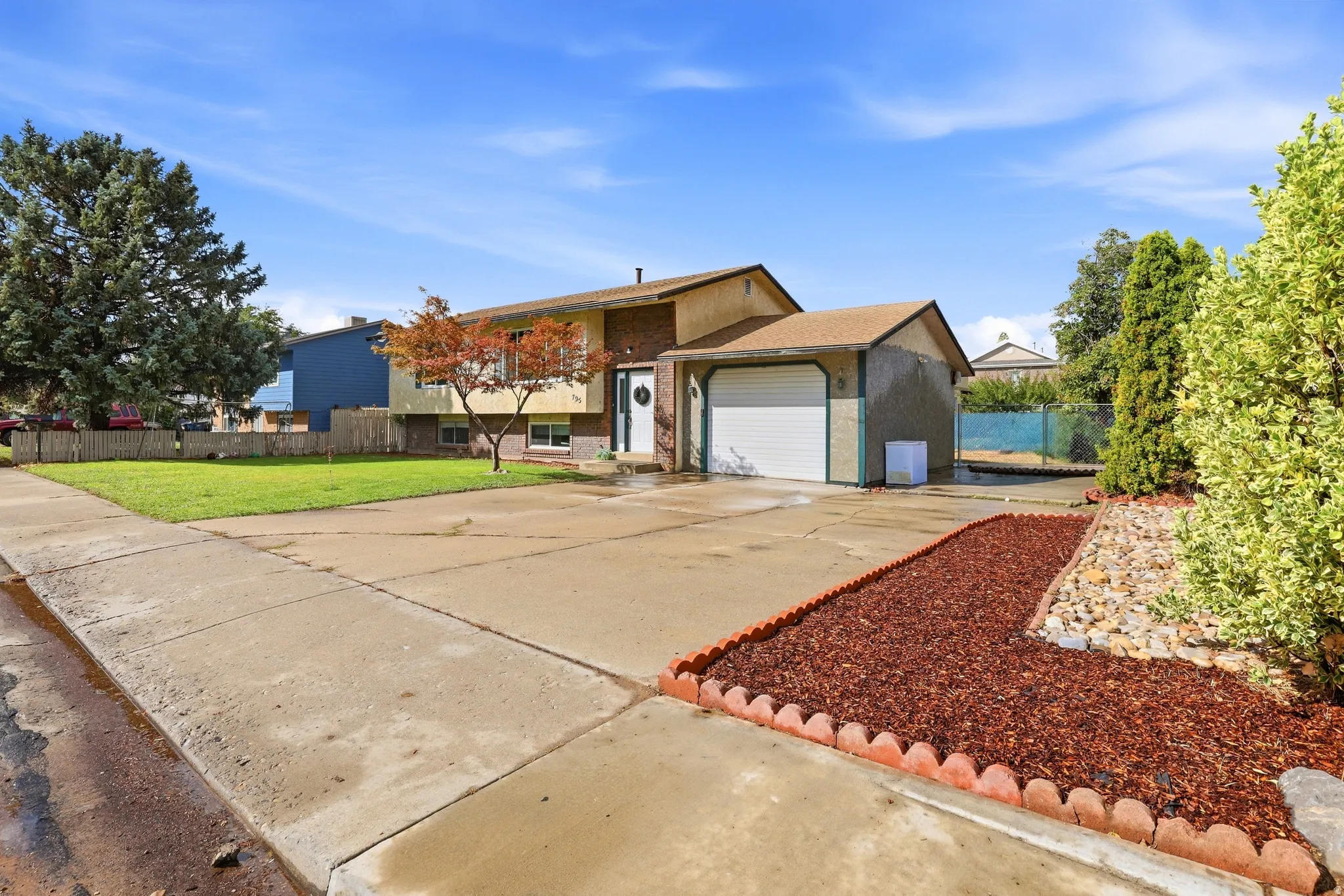 Split-level residence featuring a single-car garage and a paved driveway