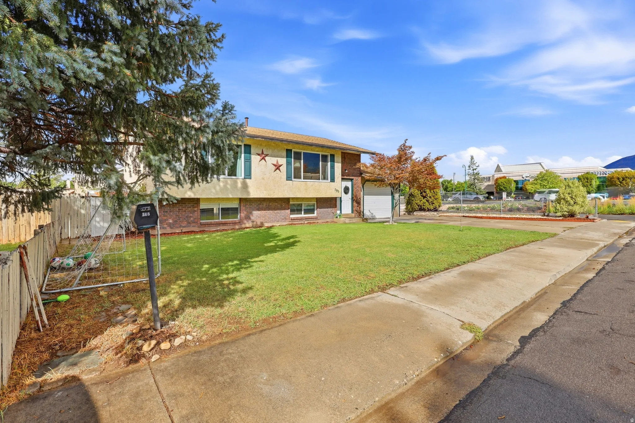 Split-level residence featuring a brick and stucco exterior, front-facing windows with shutters, and an attached garage
