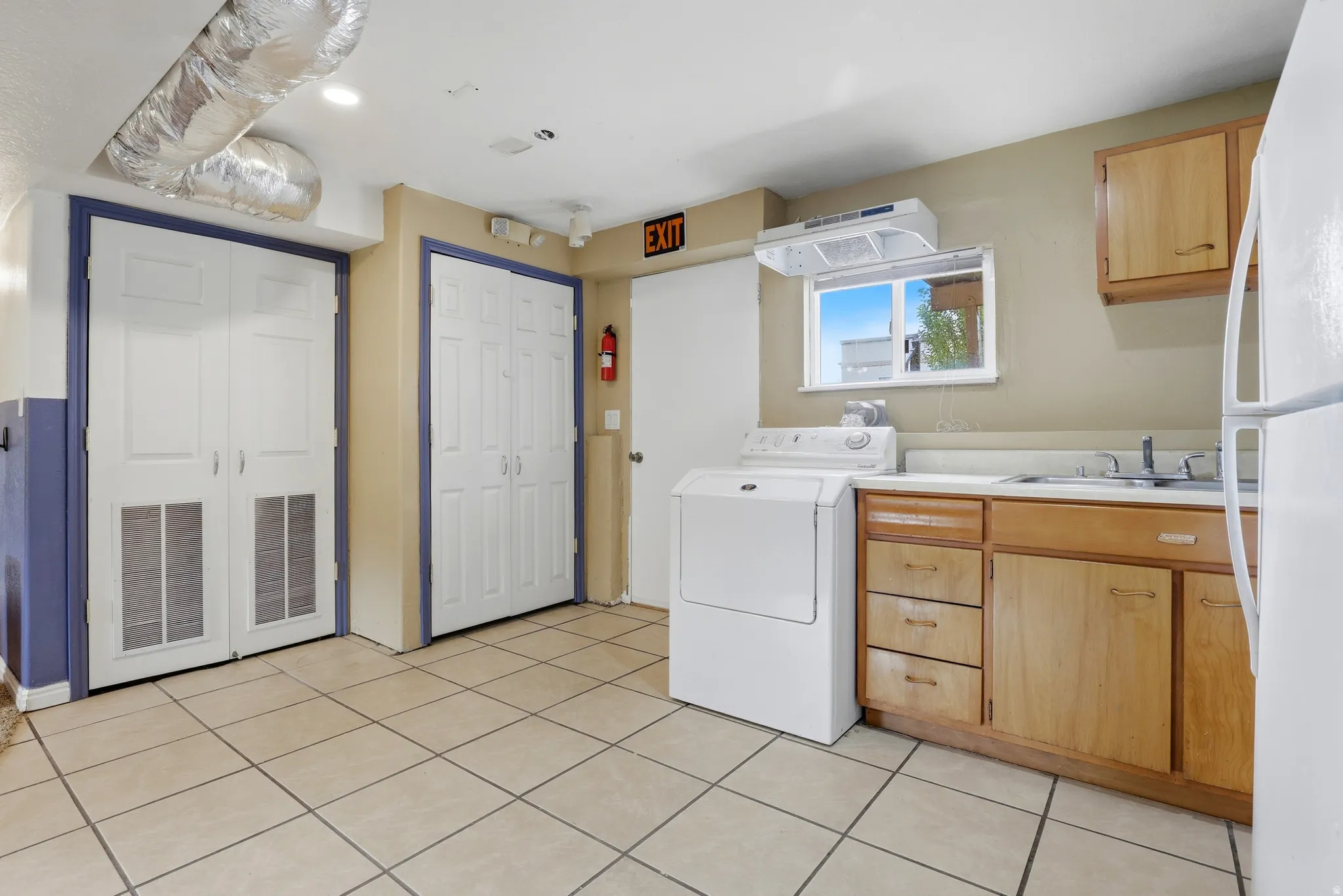 Tile flooring, light wood cabinetry, white appliances, and a window