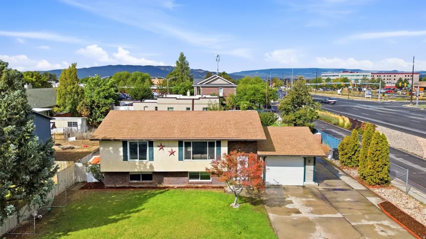Manicured front lawn, mature trees, attached garage, and paved driveway