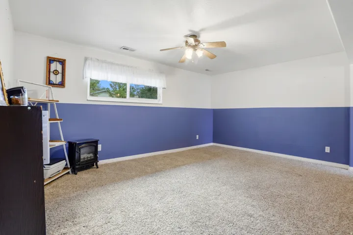 Carpeted interior space with a ceiling fan, a window, and two-tone painted walls