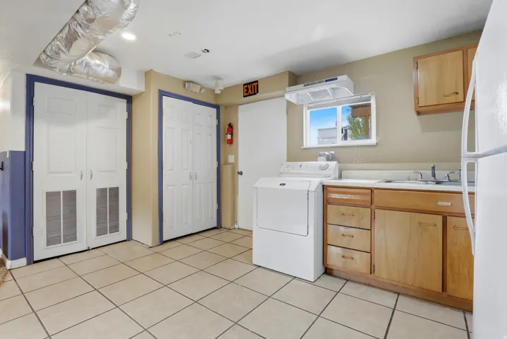 Tile flooring, light wood cabinetry, white appliances, and a window