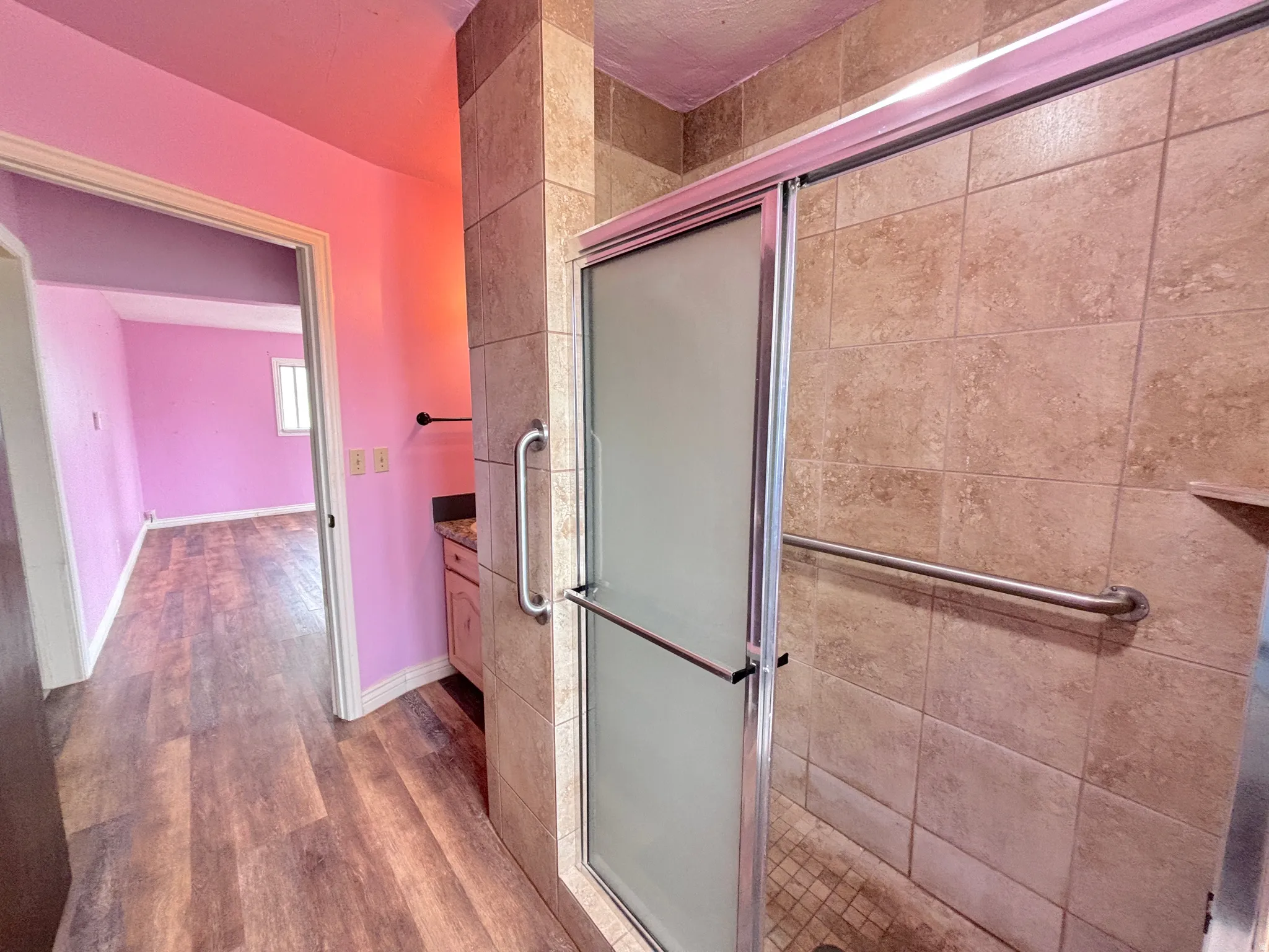 Shower enclosure with frosted glass door, tile surround, and grab bars
