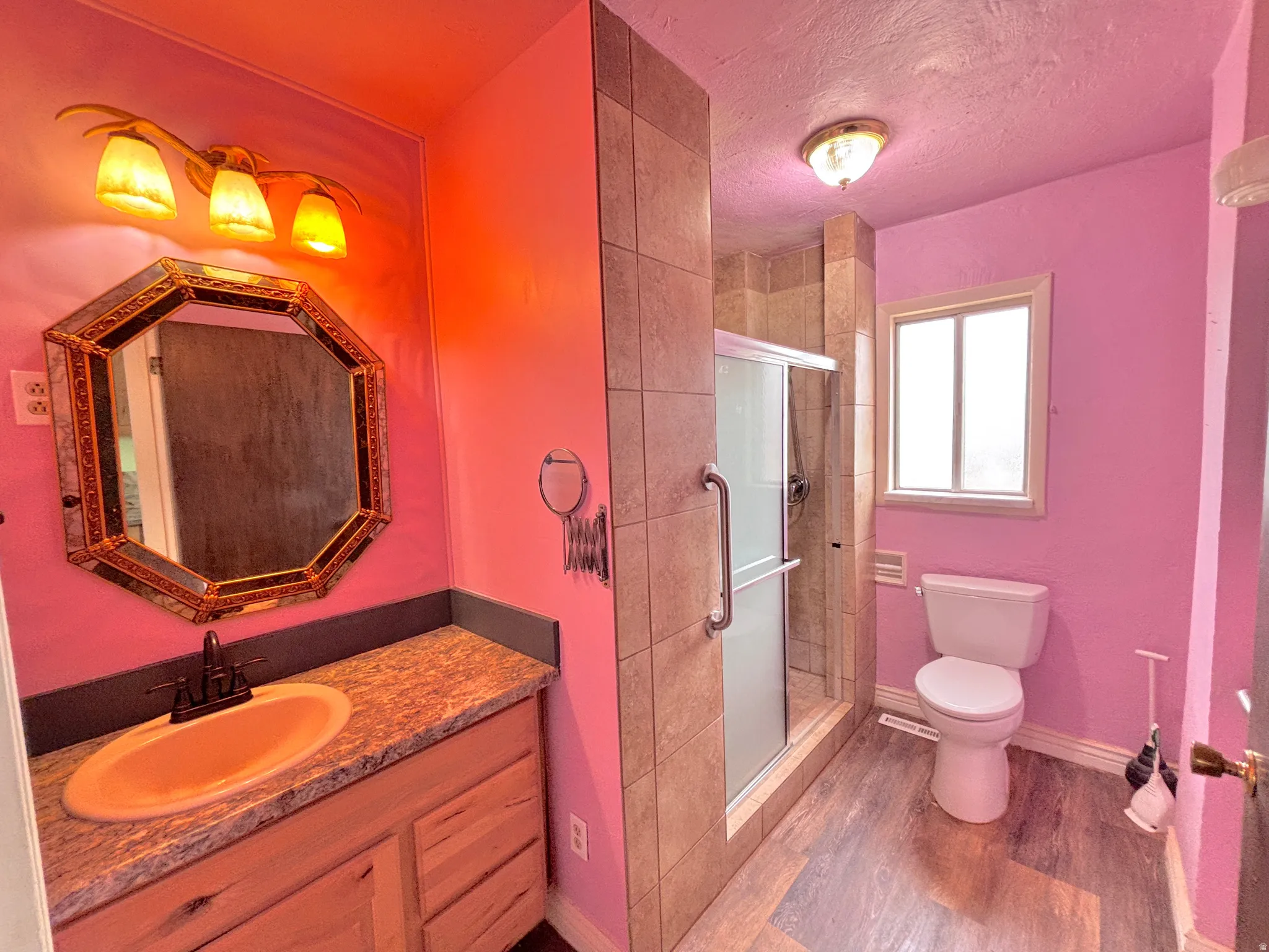 Vanity with a granite-style countertop, wood-finish cabinetry, and an ornate framed mirror
