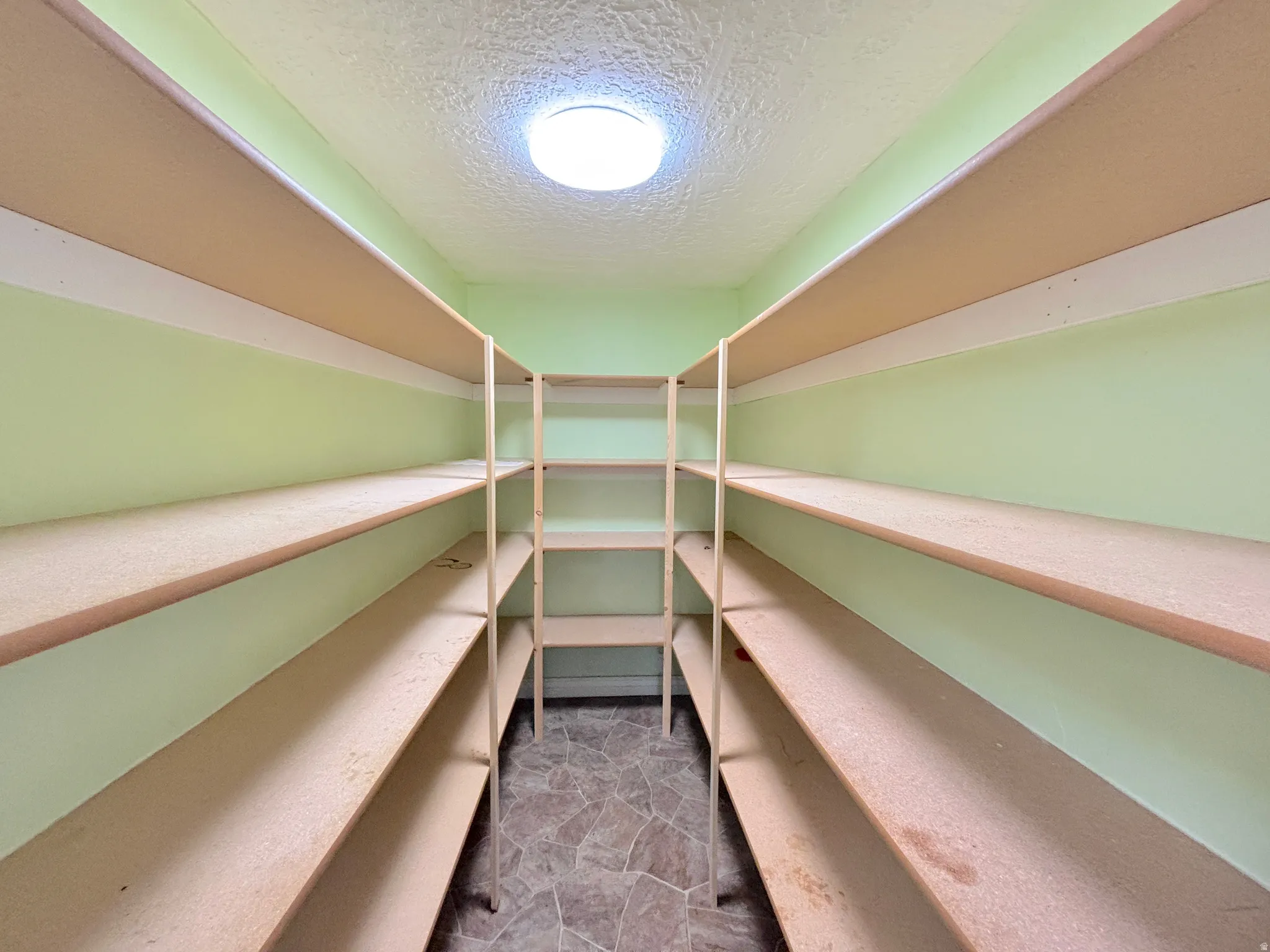 Built-in shelving units, ceiling-mounted light fixture, textured ceiling, tiled flooring