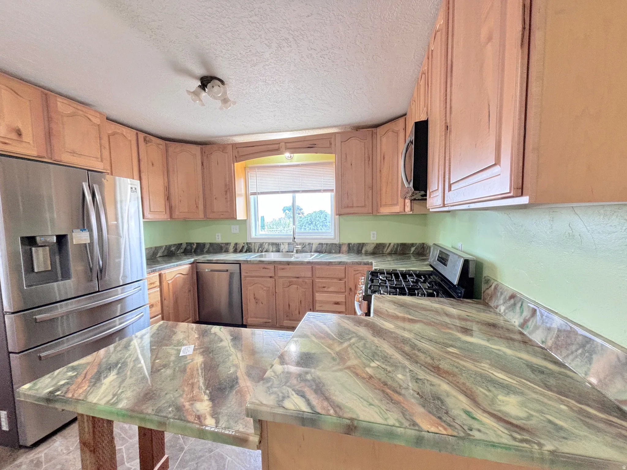 Kitchen featuring wood cabinetry, stainless steel appliances, and patterned countertops