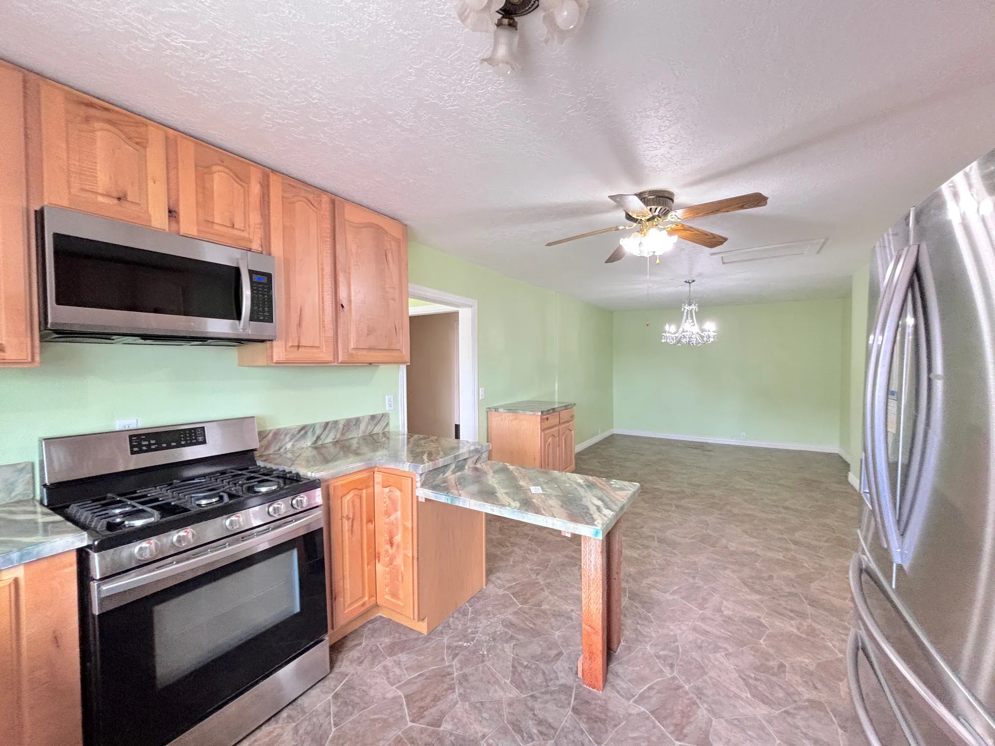 Kitchen featuring wood cabinetry, stainless steel microwave, stainless steel range, and stone-finish countertops