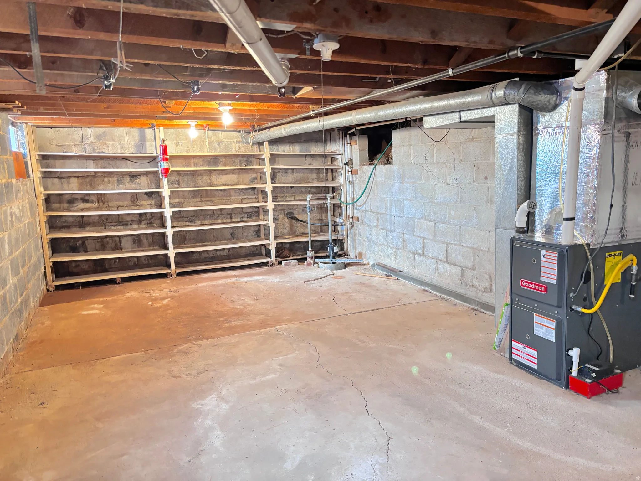 Utility room featuring exposed ceiling joists, concrete block walls, and a forced air furnace