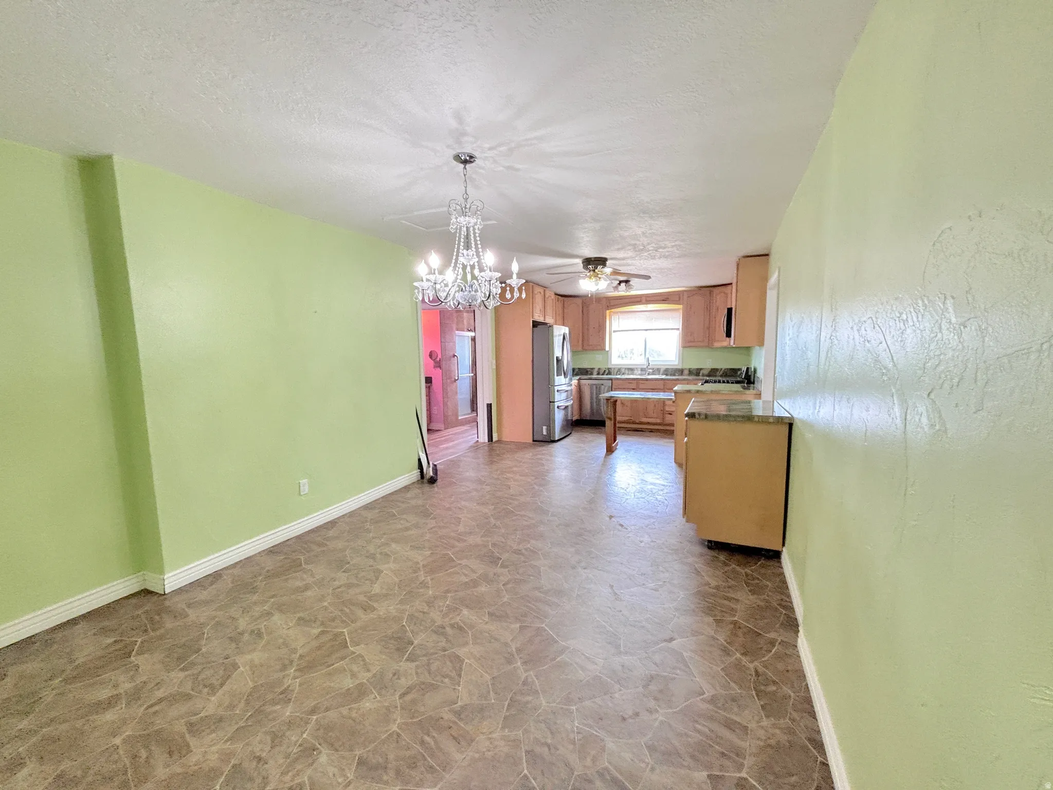 Spacious room featuring a decorative chandelier, ample light-toned cabinetry, and integrated appliances