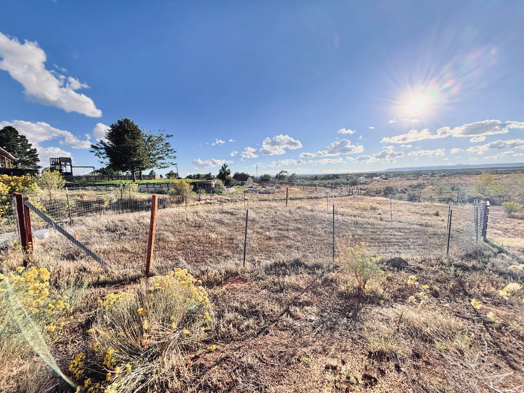 Fenced perimeter, natural landscape, distant horizon, clear sky, sparse vegetation