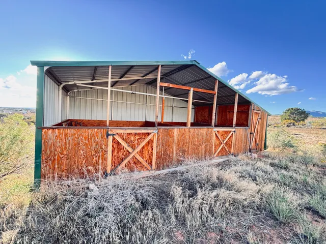 Metal roof structure with wood-panel siding and an attached wood-paneled storage shed