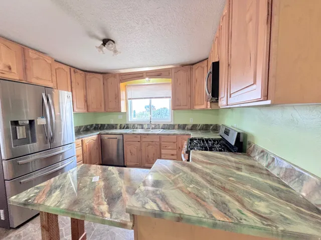 Kitchen featuring wood cabinetry, stainless steel appliances, and patterned countertops