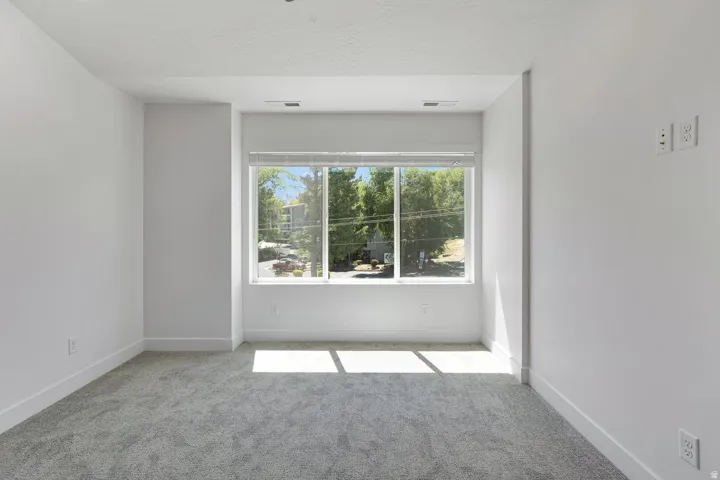 Recessed window with multiple panels, grey carpet flooring, and white painted walls