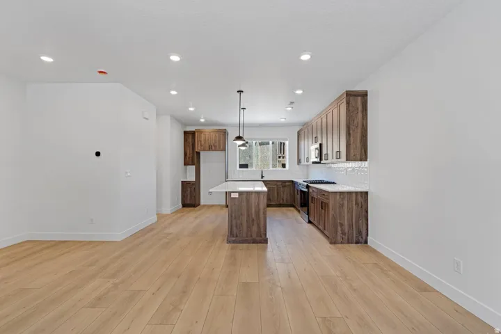 Open-concept kitchen and living area featuring wood-finish flooring, recessed lighting, and a kitchen island with white countertop