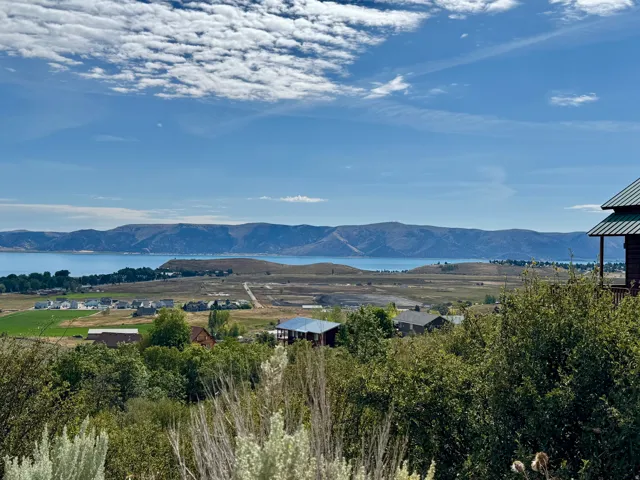 Expansive water body, distant mountains, scattered residential buildings, and diverse vegetation