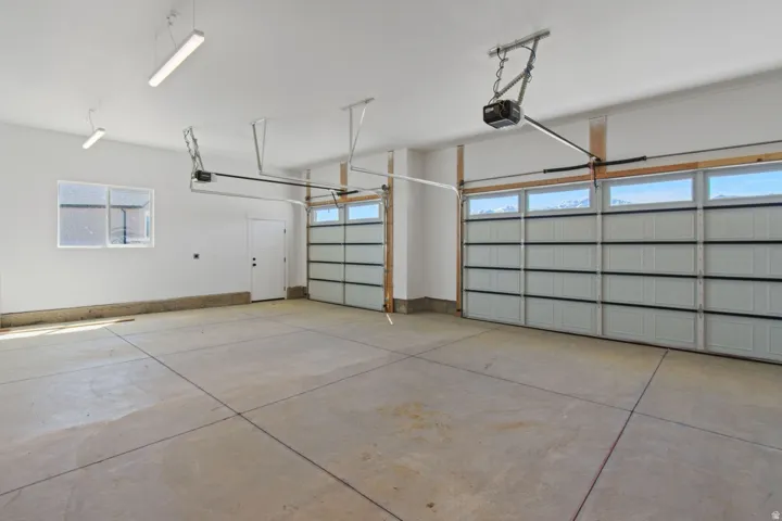 Attached two-car garage with concrete flooring, two automatic garage doors, and overhead lighting