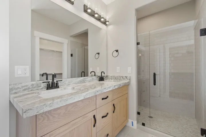 Dual vanity with light wood-finish cabinetry and stone countertop