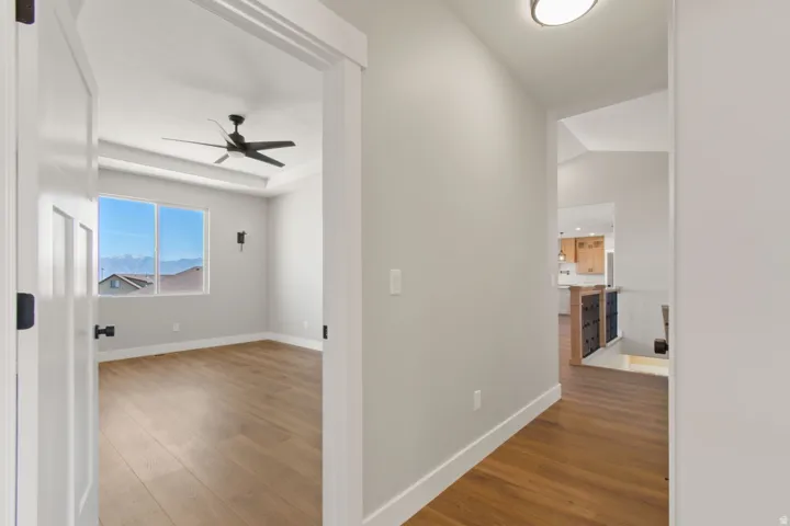 Room with wood-finish flooring, a tray ceiling, and a ceiling fan