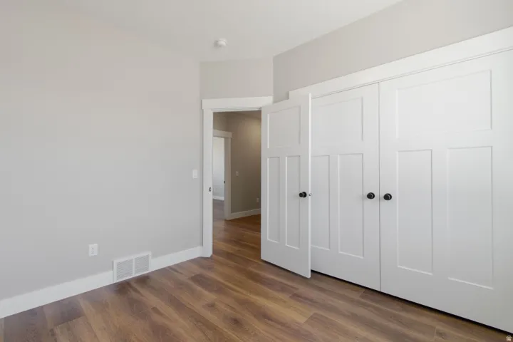 Wood-finish flooring, white trim, light gray walls, and white paneled doors with black hardware