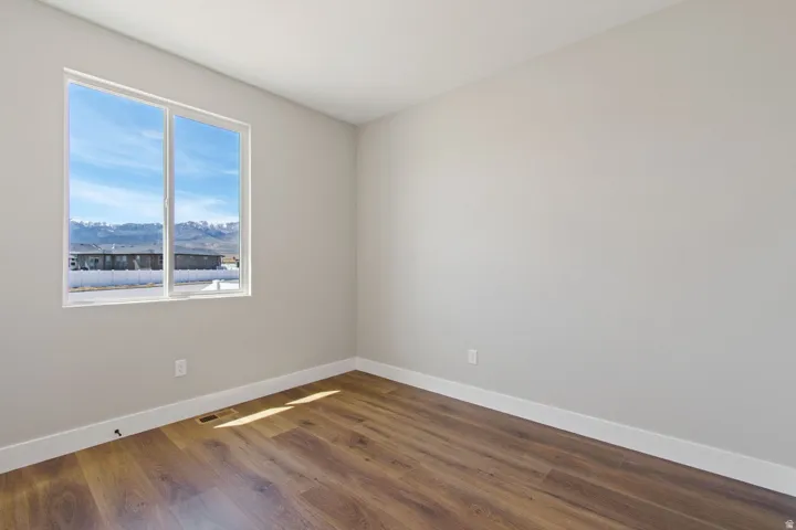 Large window with mountain scenery, wood-finish flooring, and light neutral wall color