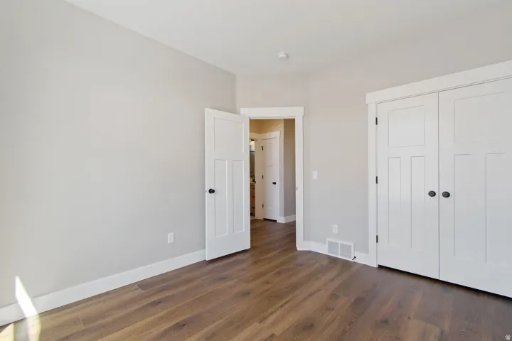 Wood-finish flooring, light gray walls, white trim, and white doors with dark hardware