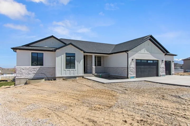 Contemporary ranch-style exterior with a dark shingle roof, white stucco siding, light stone veneer accents, and a two-car garage