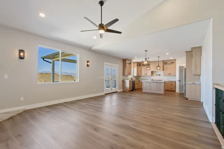 Open-concept living space featuring wood-finish flooring, vaulted ceilings, recessed lighting, and a modern ceiling fan