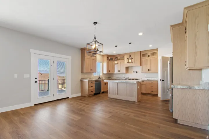 Kitchen featuring light wood-finish cabinetry, a central island with countertop, and pendant lighting