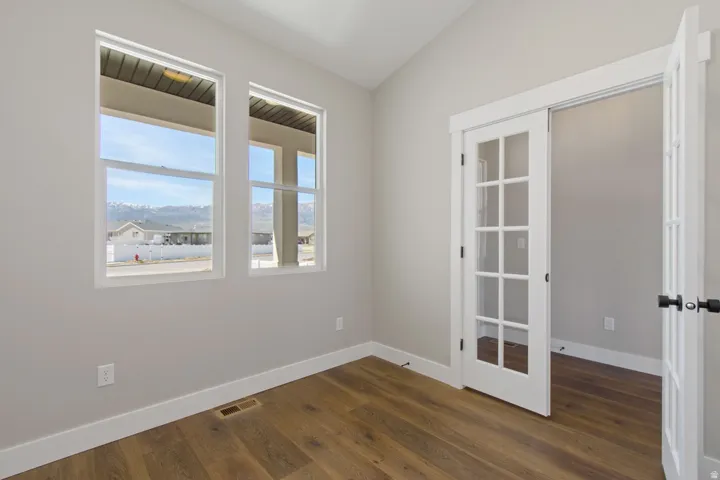 Two large windows, wood-finish flooring, white trim, and a French door with matte black hardware