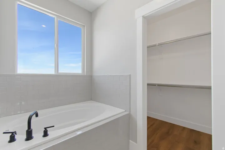 Alcove tub with matte black fixtures, white subway tile surround, and a large window