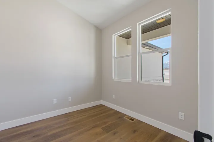 Two windows, wood-finish flooring, and light-toned walls