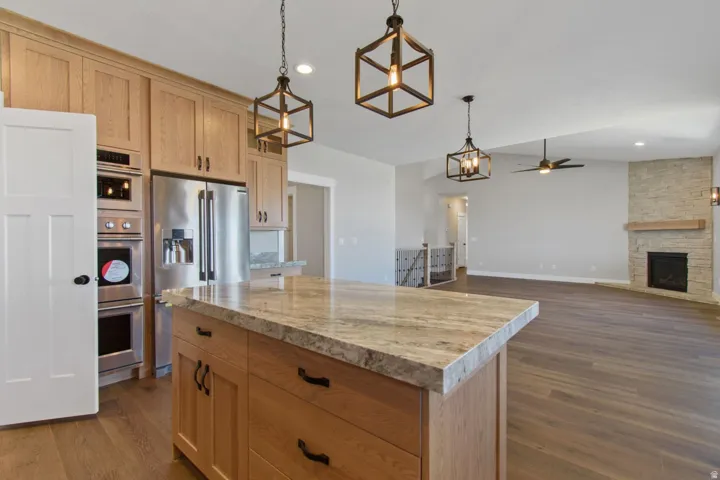 Kitchen island with stone-finish countertop, wood cabinetry, and stainless steel appliances