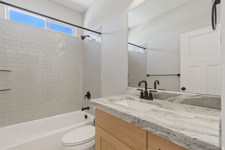 Tub-shower combination with subway tile surround, floating vanity with an integrated sink, and black fixtures