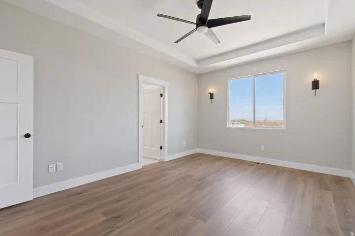 Wood-finish flooring, tray ceiling, and a contemporary ceiling fan