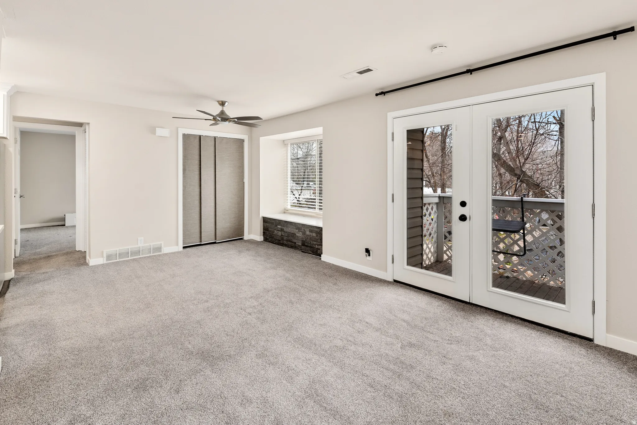 Carpeted living area with a ceiling fan, dual French doors, and a built-in window seat