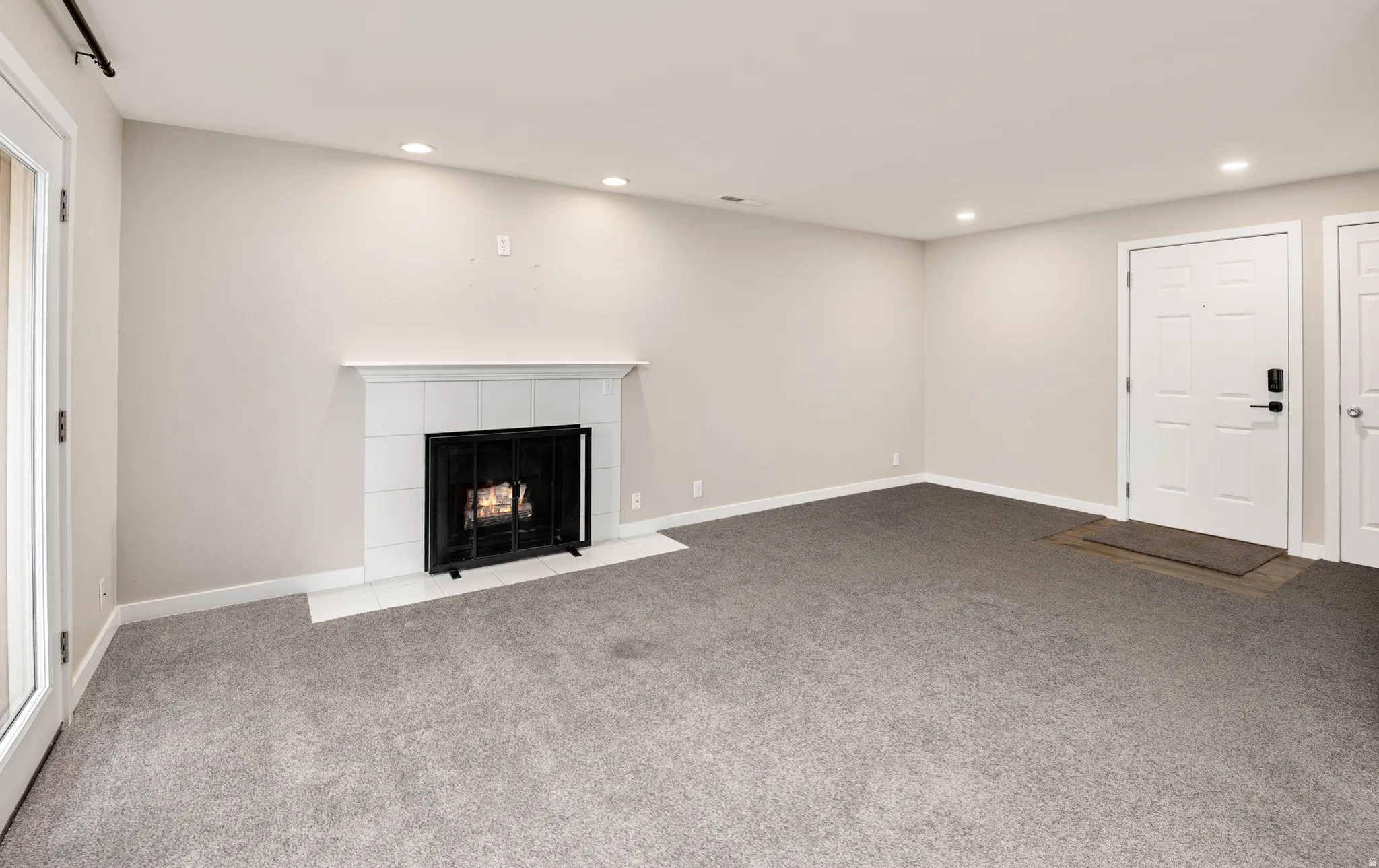 Recessed lighting, fireplace with tile surround, white mantel, and a glass-paneled exterior door
