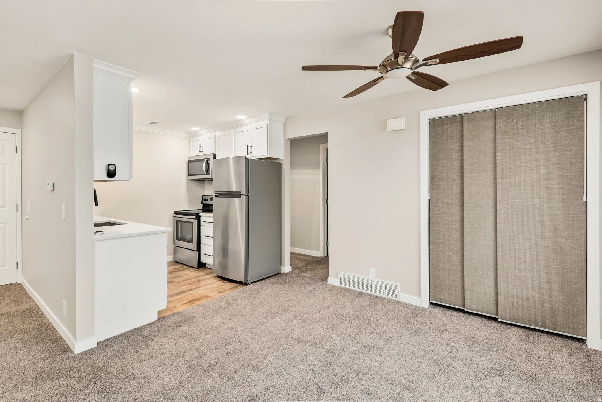 Kitchenette with white cabinetry, stainless steel appliances, and a wood-finish floor