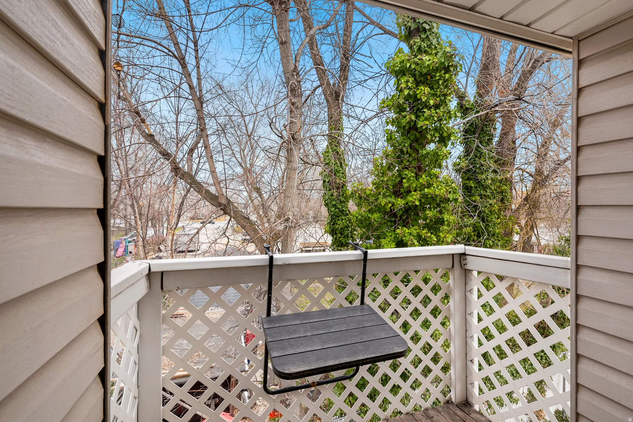 Balcony featuring white lattice railing, wood-finish flooring, and light-colored siding