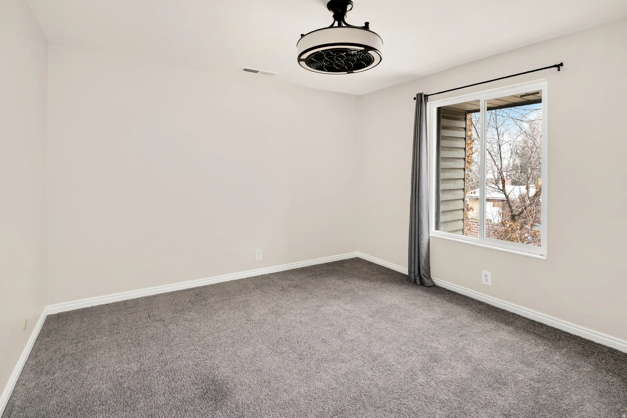 Neutral wall color, gray carpet, white trim, and a contemporary ceiling light fixture
