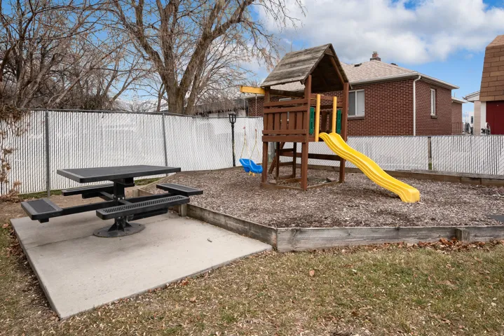 Outdoor entertainment area with a picnic table on a concrete pad, a raised play structure.