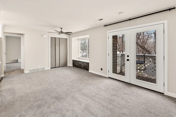 Carpeted living area with a ceiling fan, dual French doors, and a built-in window seat