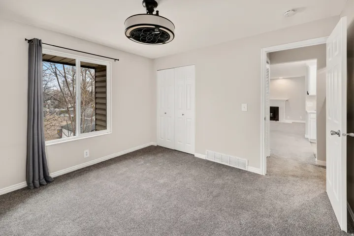 Light gray wall paint, gray carpeting, white trim, and a ceiling-mounted light fixture with fan