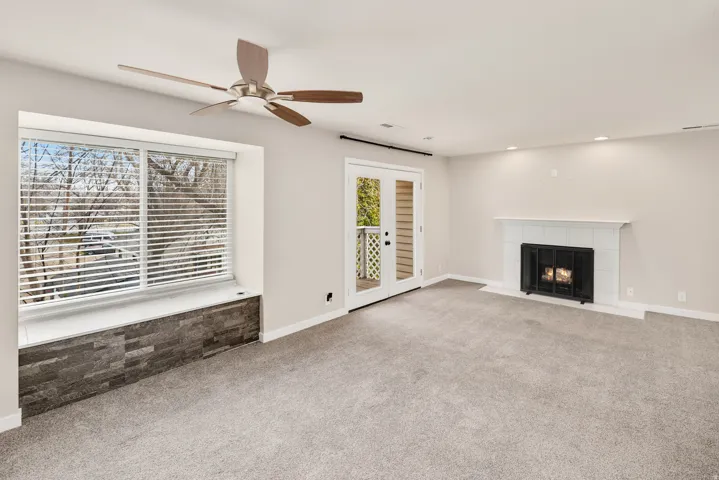Recessed lighting, ceiling fan, carpet flooring, and a fireplace with a white tile surround