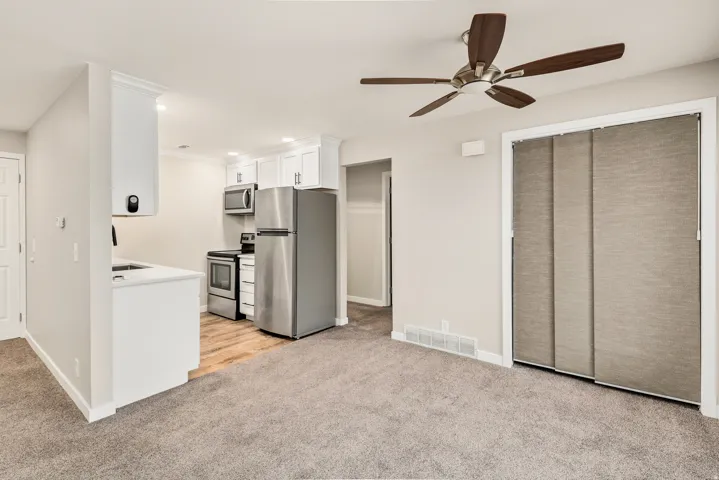 Kitchenette with white cabinetry, stainless steel appliances, and a wood-finish floor