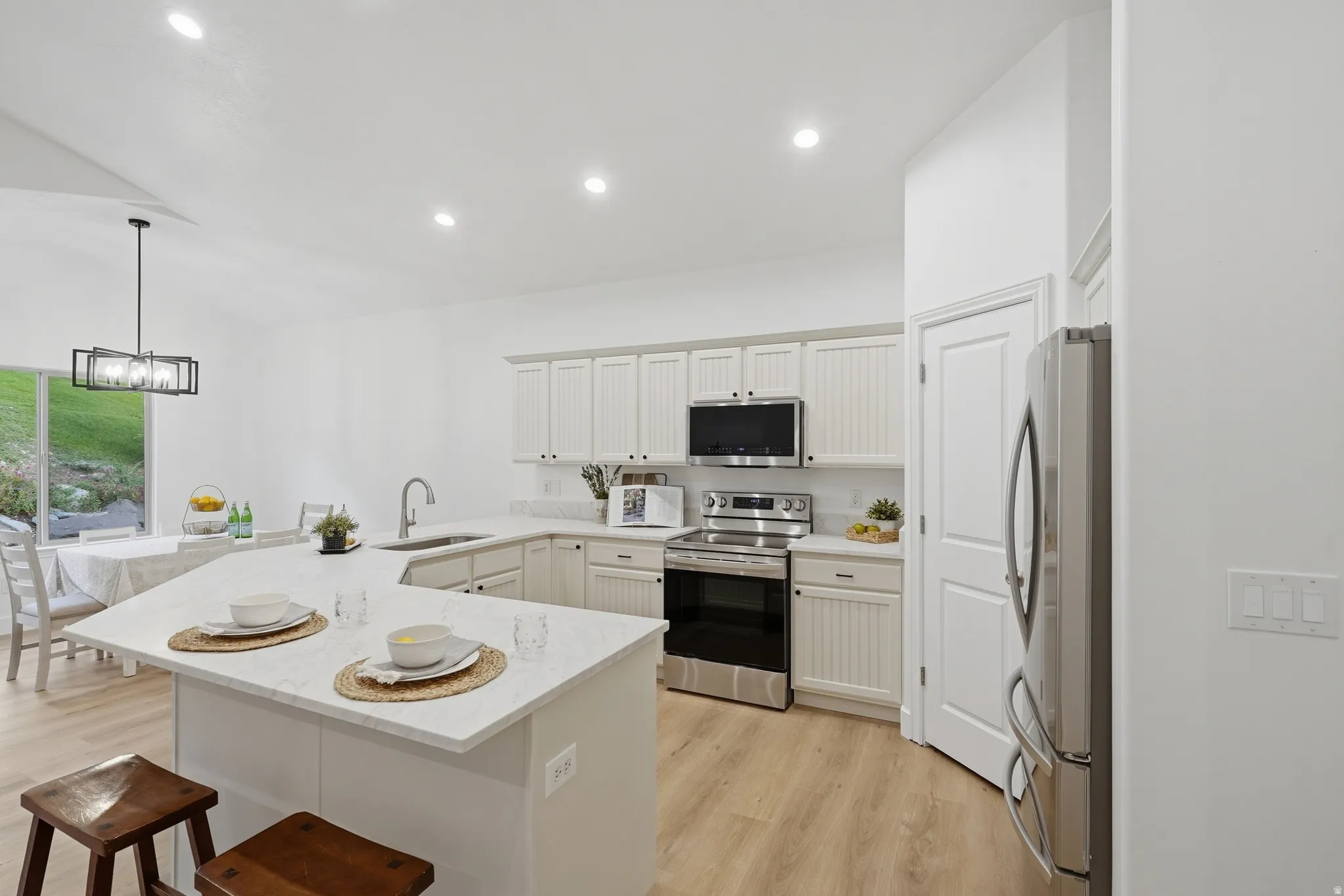 Kitchen featuring light cabinetry, stainless steel appliances, a center island with quartz countertops