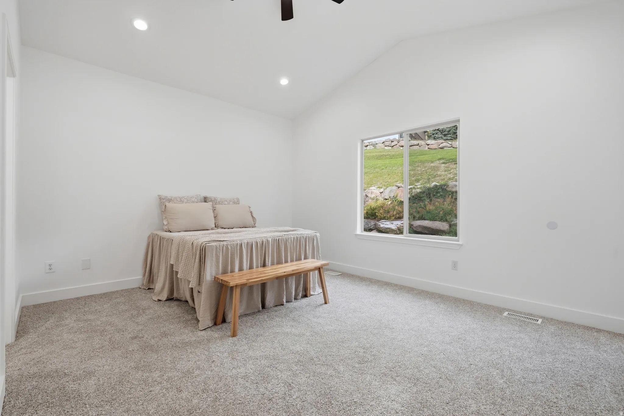 Primary bedroom with vaulted ceiling, recessed lighting, carpet flooring, large window, and ceiling fan