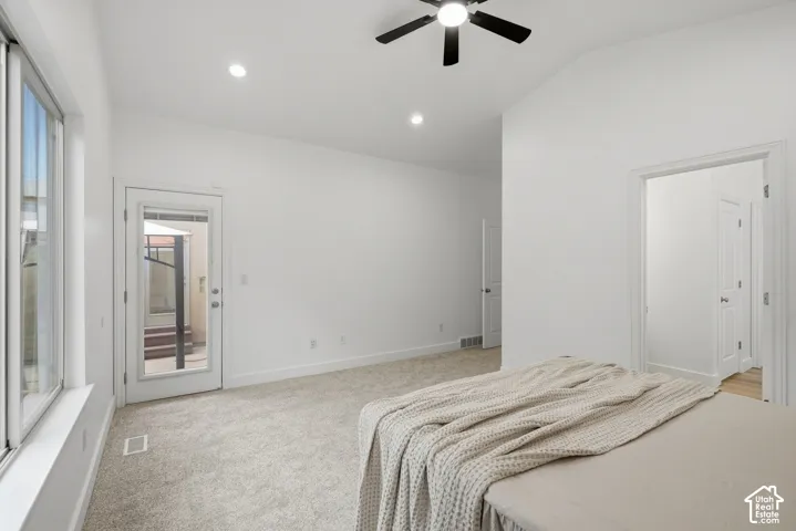 Primary bedroom with vaulted ceiling, recessed lighting, ceiling fan, carpet flooring, and a glass-paneled door leading to backyard patio